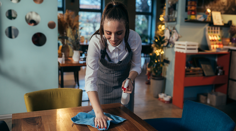 Servicekraft reinigt Gästebereich eines Restaurants 