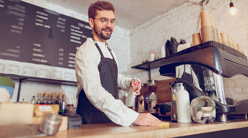 Servicekraft reinigt Ladentheke in Gastronomiebetrieb