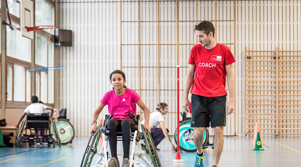 Kind im Rollstuhl und Coach machen Sport in Turnhalle