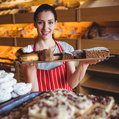 Bäckerin Konditorin mit Kuchenblech in Backstube Bäckerei