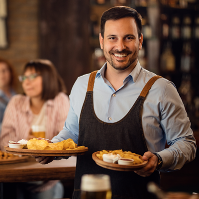 Servicekraft mit Schürze bedient Gäste mit Speisen in Restaurant Gastronomiebetrieb