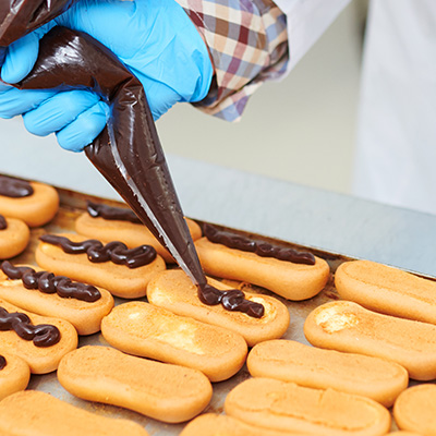 Hand dekoriert Eclairs mit Schokoladenglasur aus Spritzbeutel