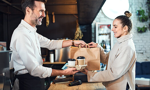 Mann überreicht Frau Take-away-Bestellung