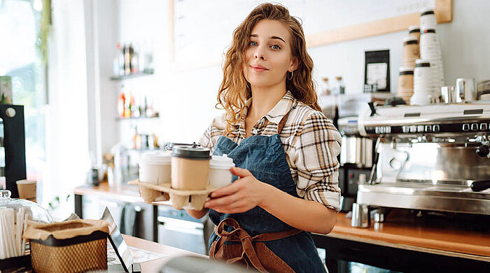 Person reicht Kaffee to Go an Kunden